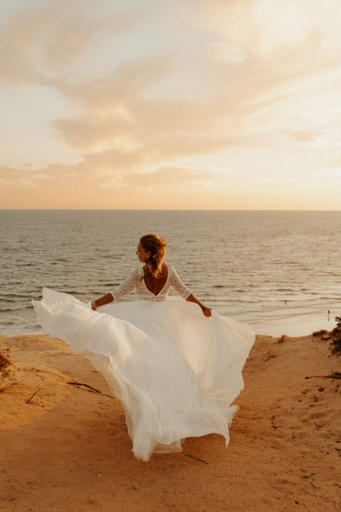 Mariée en robe blanche sur une falaise face à la mer