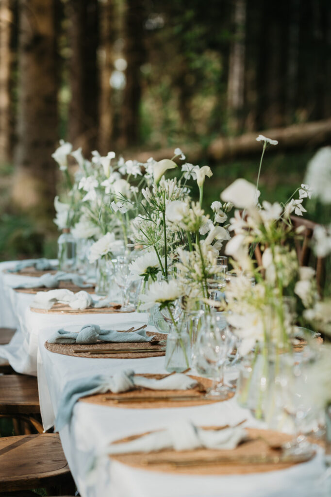 Longue table de mariage dressée avec fleurs sauvages en forêt