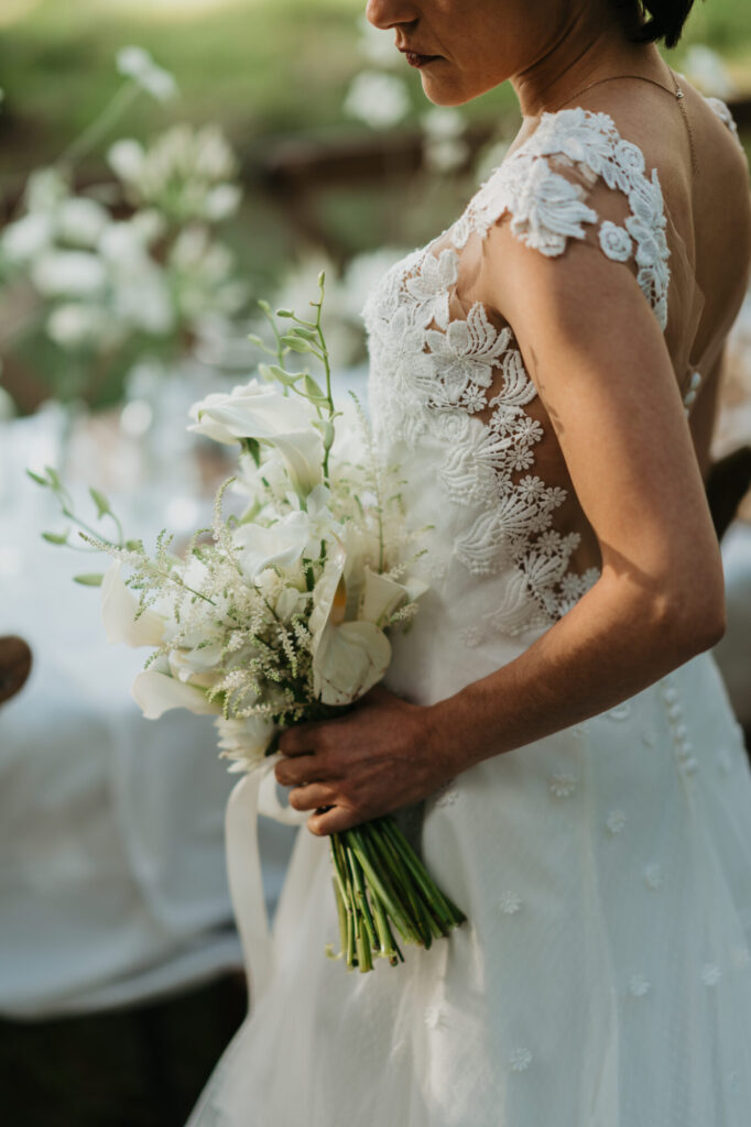 Mariée en robe blanche tenant un bouquet de fleurs blanches