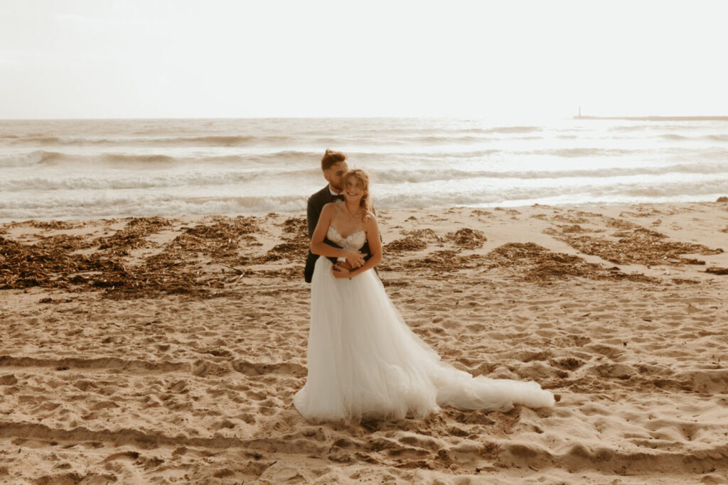 Mariée en robe blanche debout sur une plage