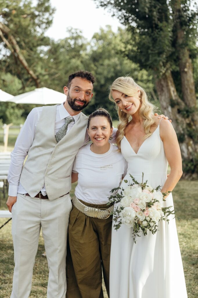 Deux mariés posent avec une femme tenant un bouquet
